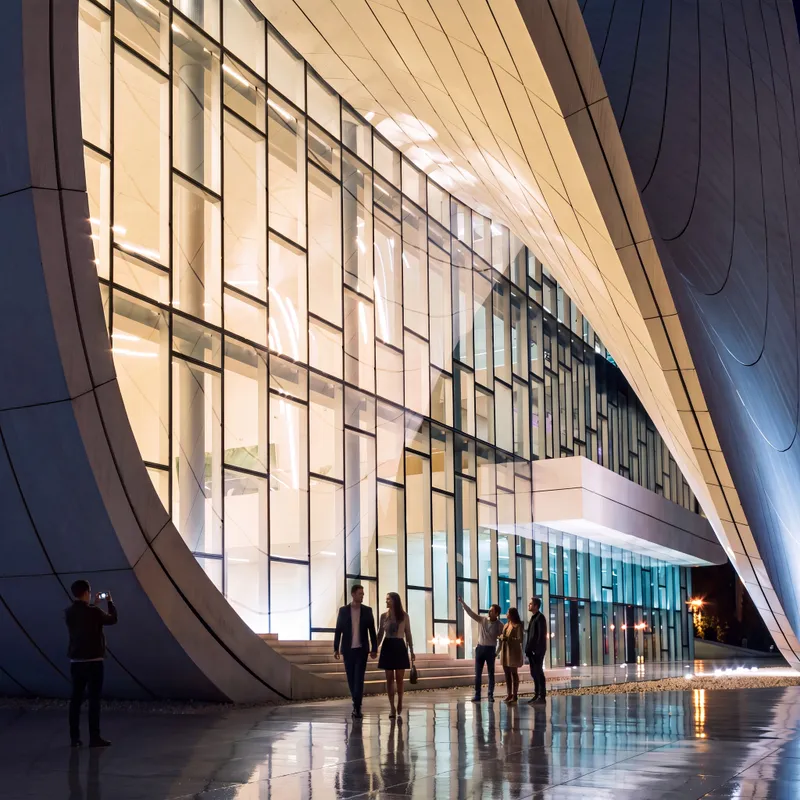 Render of a sweeping curved facade with glass wall at night