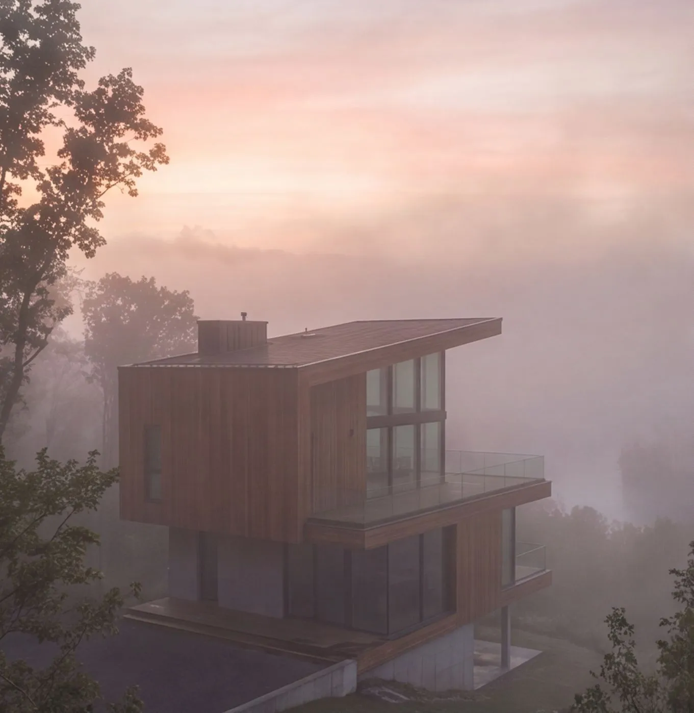 The wooden hillside house in pink morning mist